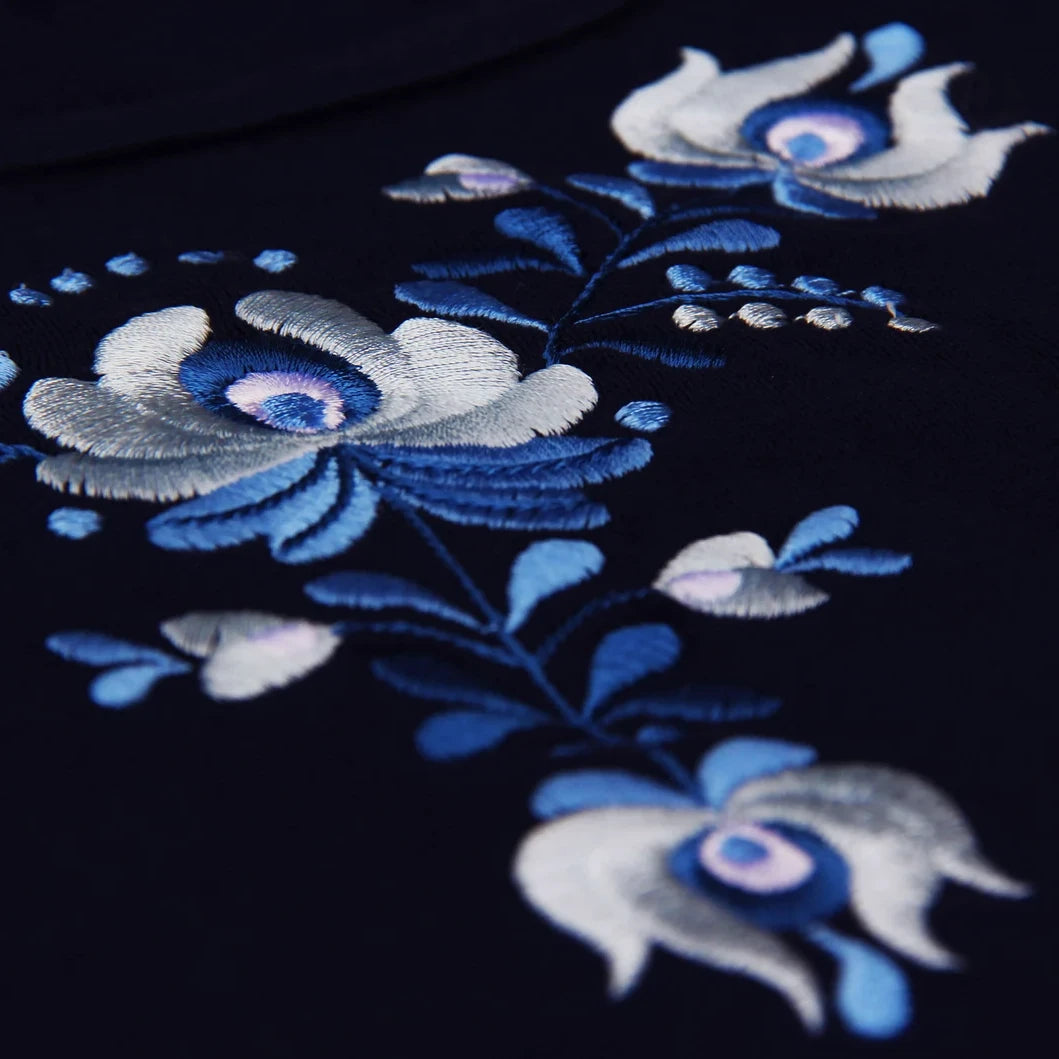 Vue en détail de la broderie hongroise de type Matyó aux nuances bleues et blanches.