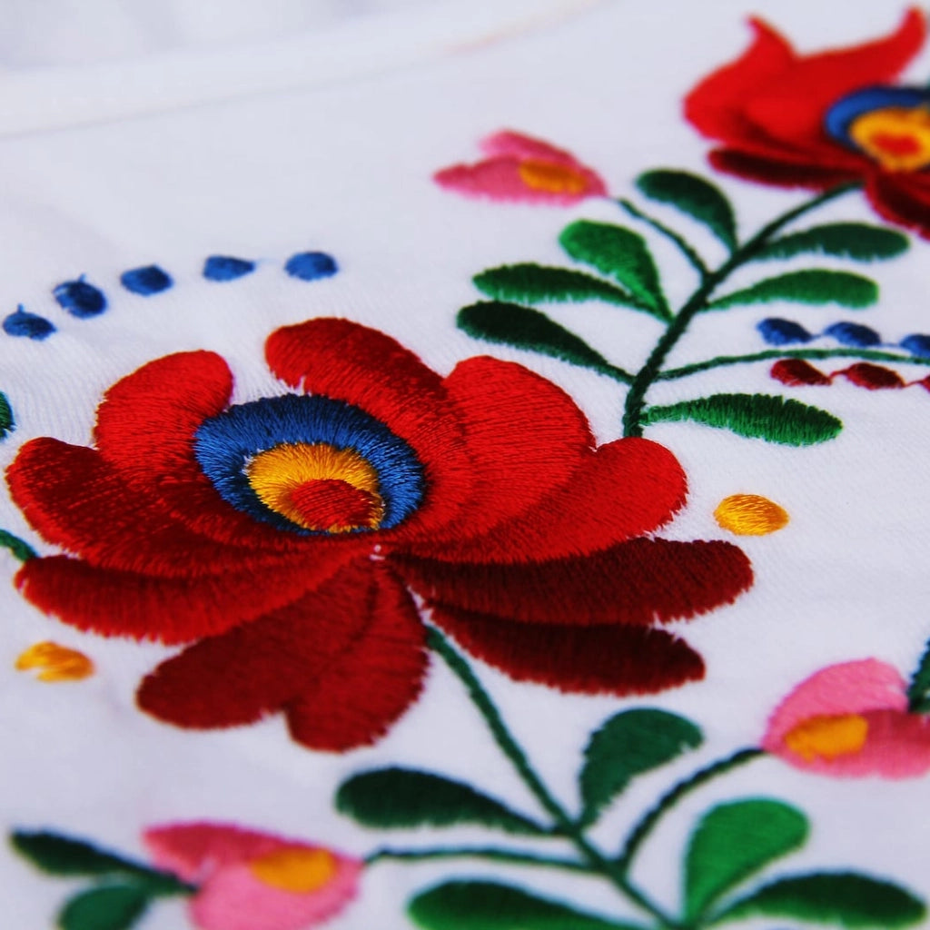 Gros plan sur la finesse de la broderie hongroise de ce t shirt blanc