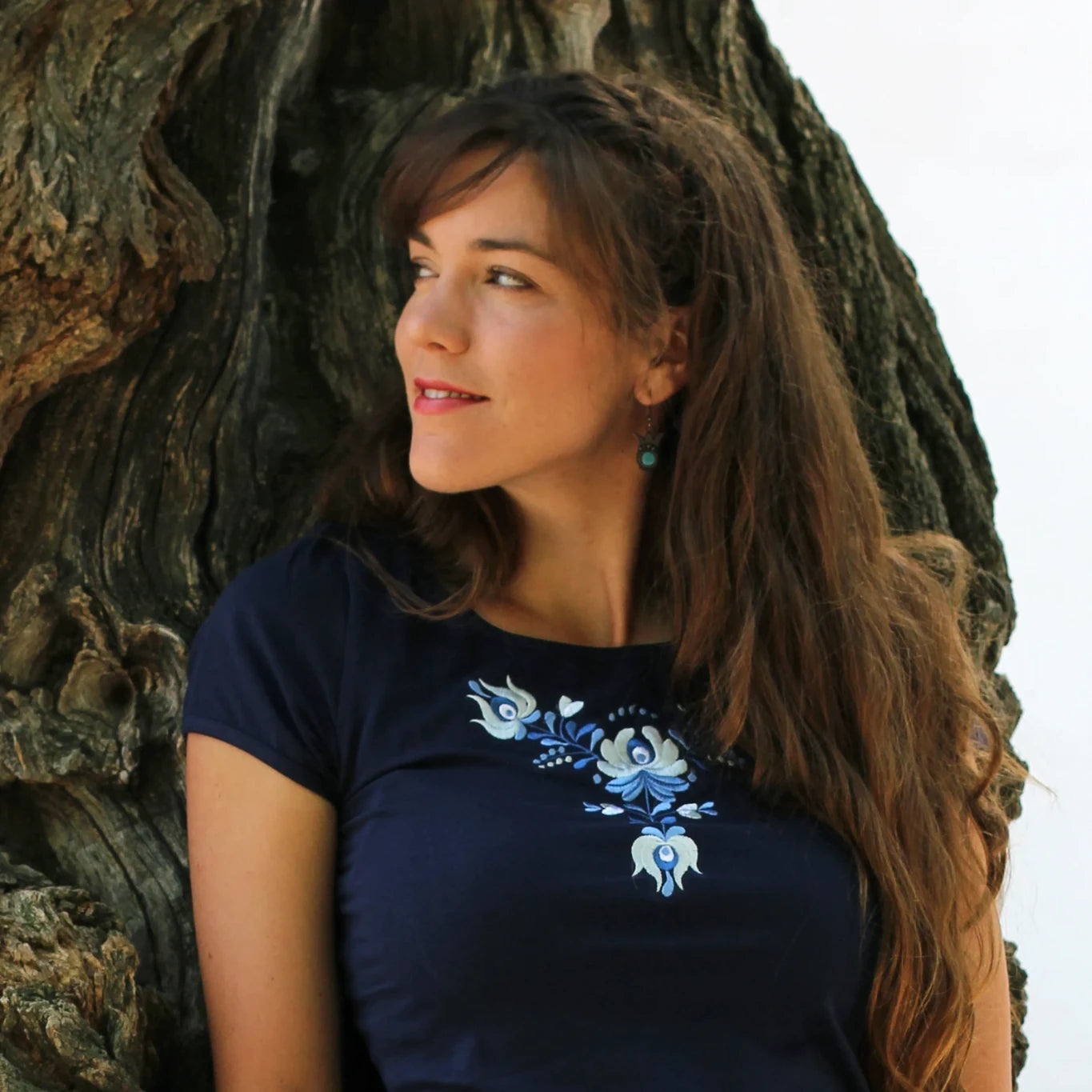 T-shirt bleu à manches courtes. Ce haut pour femme est brodé avec des fleurs Matyó dans des tons s'accordant harmonieusement avec la couleur bleue du T shirt. Photo rapprochée.