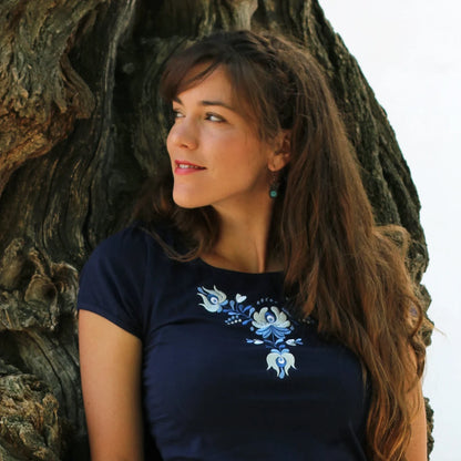 T-shirt bleu à manches courtes. Ce haut pour femme est brodé avec des fleurs Matyó dans des tons s'accordant harmonieusement avec la couleur bleue du T shirt. Photo rapprochée.