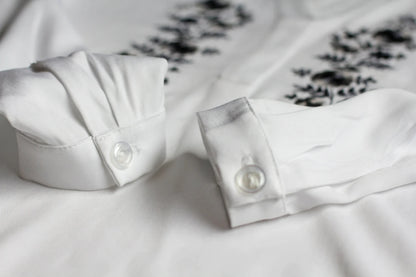 Détail des manches de la blouse. En arrière-plan on voit les fines broderies blanches et gris-argenté d'inspiration Palóc.