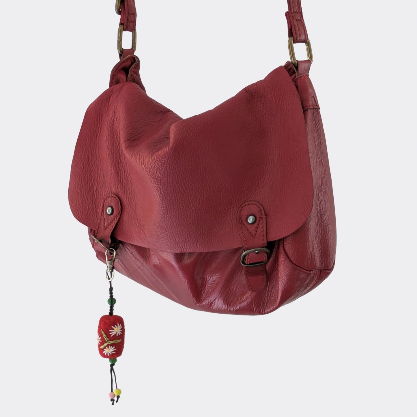 Charm artisanal serbe en laine feutrée accroché à un sac rouge
