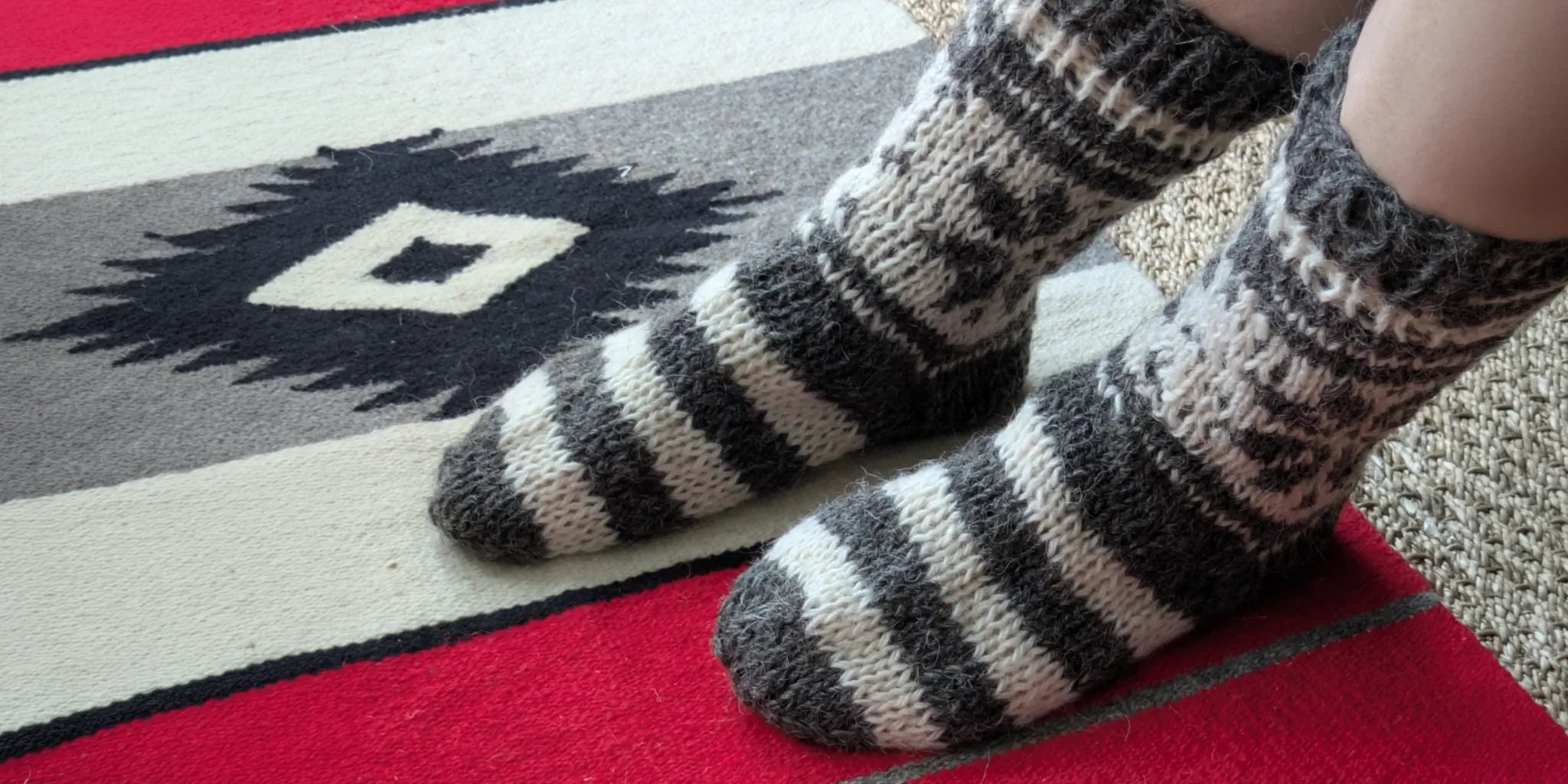 Vue de chaussettes grises avec rayures portées en intérieur. Chaussettes 100% laine tricotées à la main.