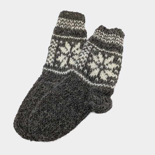 Chaussettes en laine grise sans rayures, avec motifs écrus sur le haut. La texture tricotée main est visible. Modèle simple de chaussettes chaudes 100% laine.