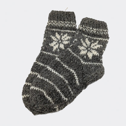 Chaussettes grises en laine avec rayures écrues et motif géométrique sur la tige. La texture est épaisse et rustique. Modèle de chaussettes chaudes en laine.