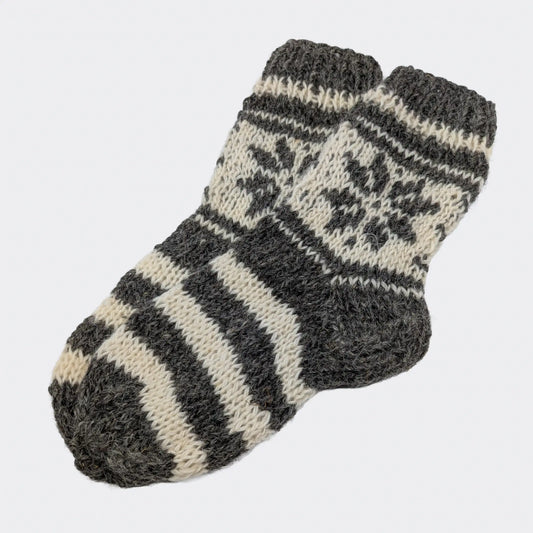 Chaussettes grises rayées en laine de mouton, avec pied rayé gris et écru. La tige présente un motif géométrique clair. Un modèle épais de chaussettes en laine du Podhale.