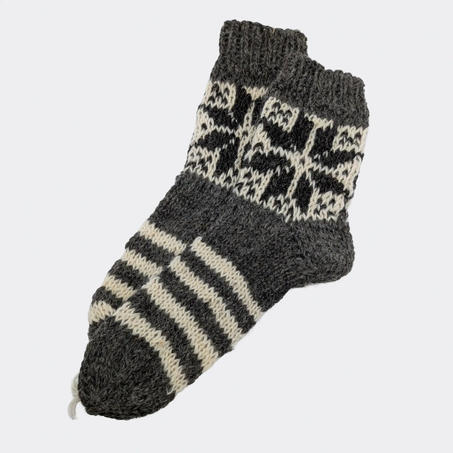 Chaussettes grises en laine avec rayures écrues et motif géométrique sur la tige. La texture est épaisse et rustique. Modèle de chaussettes chaudes 100% laine.
