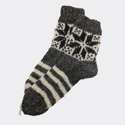 Chaussettes grises en laine avec rayures écrues et motif géométrique sur la tige. La texture est épaisse et rustique. Modèle de chaussettes chaudes 100% laine.