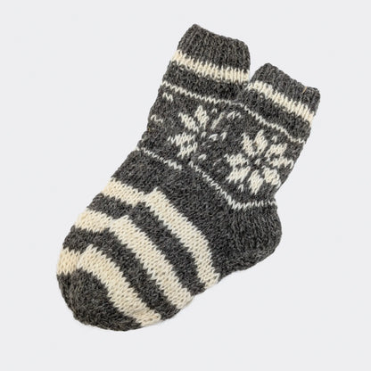 Chaussettes grises avec rayures écrues larges en laine, tige ornée de motifs géométriques écrus. Texture épaisse et naturelle.