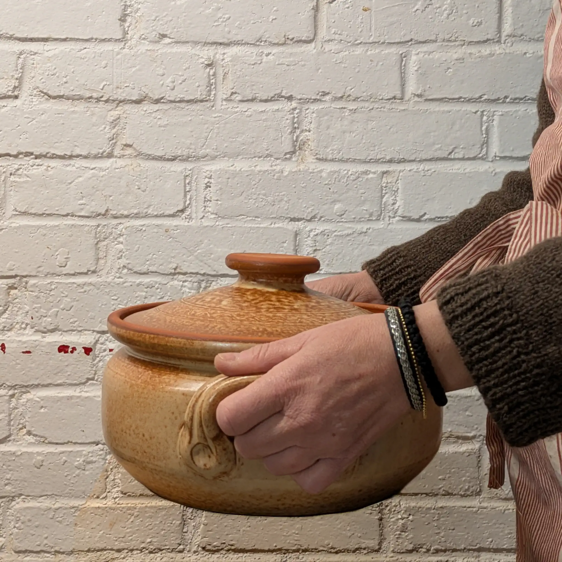 Cocotte artisanale de Corund 5 litres tenue dans les mains, poterie traditionnelle pour cuisine familiale et plats mijotés.