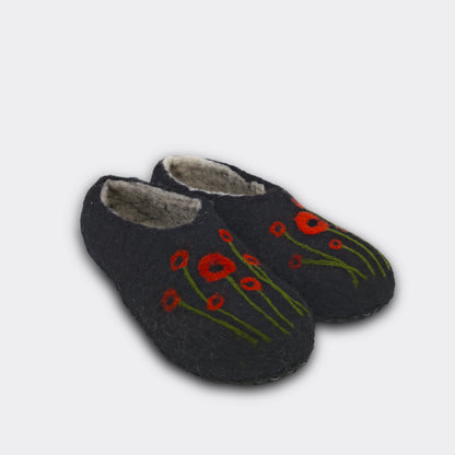 Photo de chaussons noirs vus de biais. Des coquelicots ornent ces chaussons pour ajouter une touche de couleur.