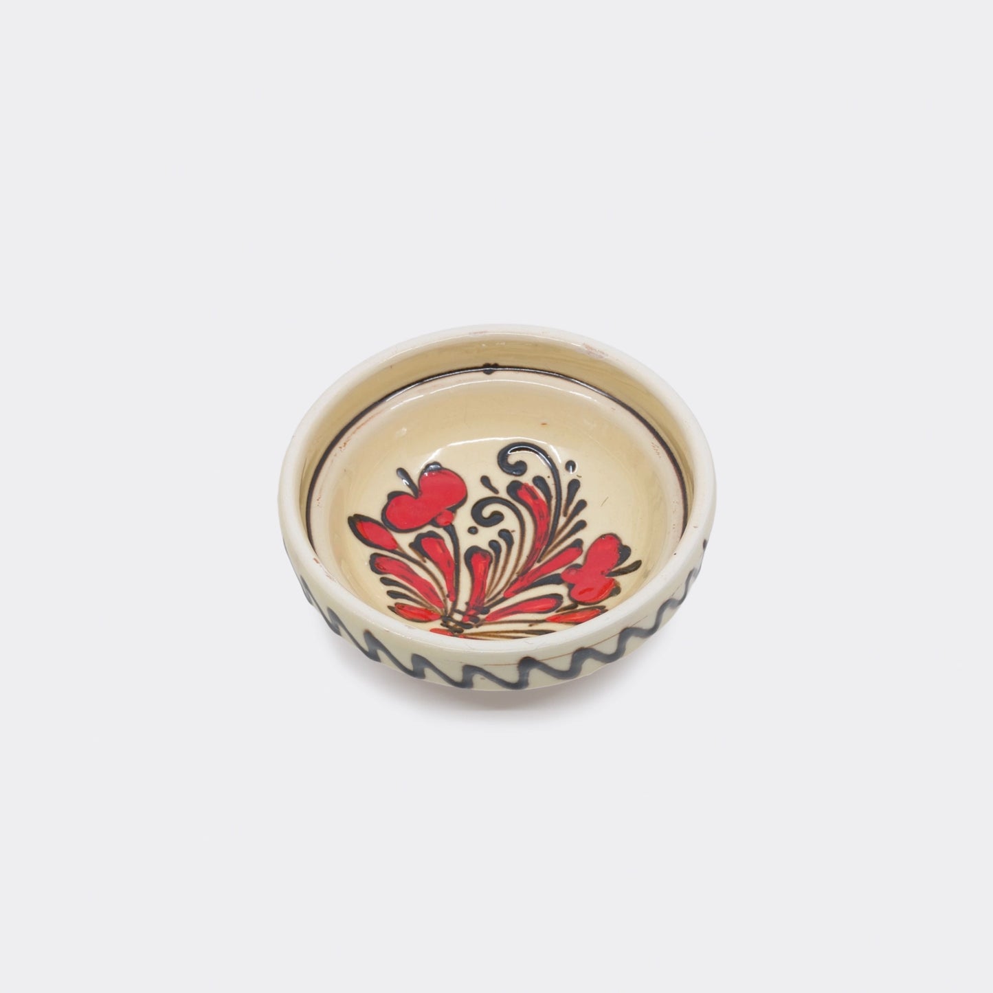 Coupelle en céramique de Corund vue du dessus. Motifs tulipes rouges et brun-noir sur fond crème. Faïence artisanale peinte à la main.