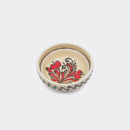 Coupelle en céramique de Corund vue du dessus. Motifs tulipes rouges et brun-noir sur fond crème. Faïence artisanale peinte à la main.