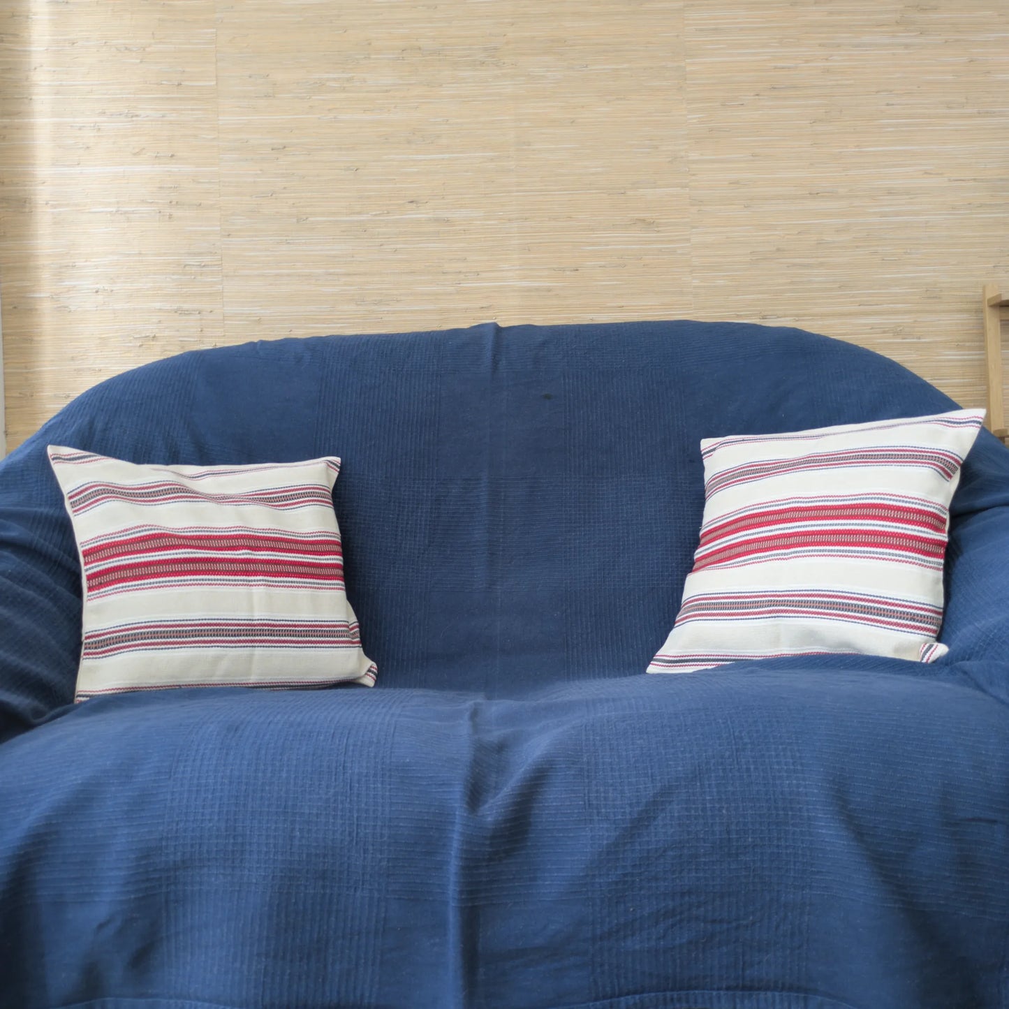 Deux coussins dans une housse en coton tissé faite à la main de République Tchèque 40x40. Vue sur un canapé. Housses couleur crème et rouge.