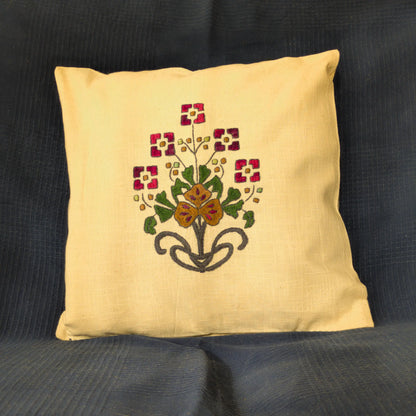 Housse en lin naturel brodée main avec un bouquet composé. Les fleurs géométriques rouges entourent une fleur centrale ocre. Un motif équilibré.