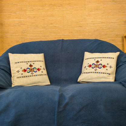 Broderie typique du Kosovo appliquée sur deux coussins en lin. Visuel sur un canapé.