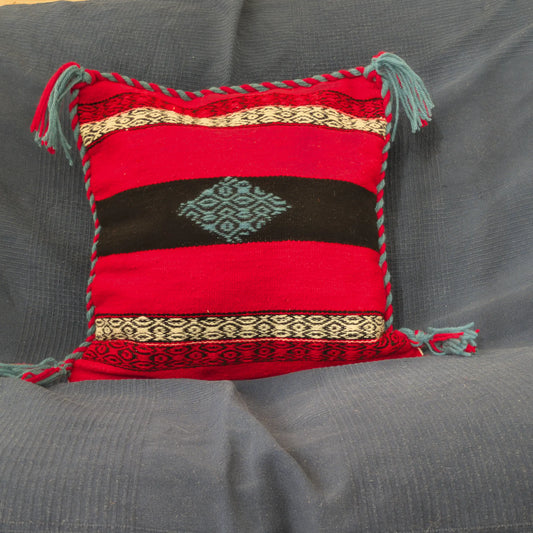 Housse de coussin rouge et noir en laine tissée à la main. Bord tressé discret et pompons.