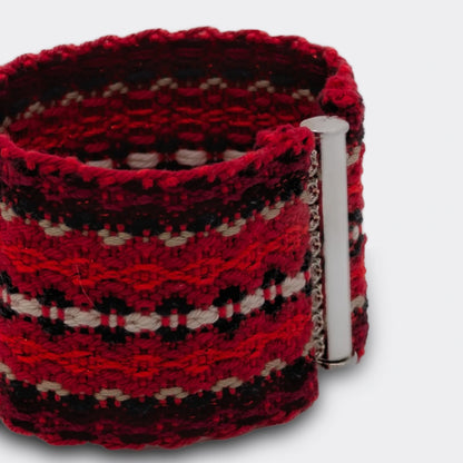 Détail d'un bracelet tissé rouge, ton sur ton, avec une ligne centrale blanche. D'inspiration folklorique des Balkans.