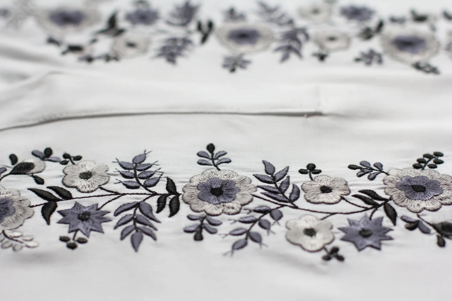 Détail de la broderie de la blouse blanche. les tons blancs et gris argentés s'accordent parfaitement pour ce haut brodé dans la plus pure tradition hongroise.