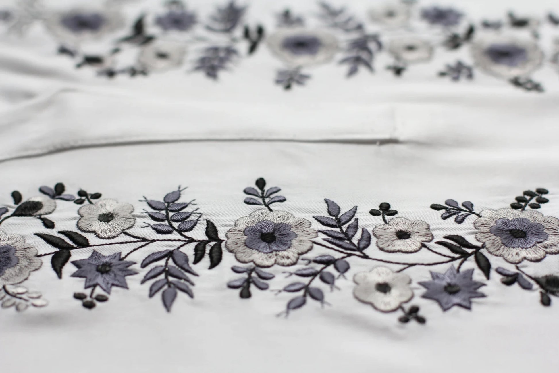 Détail de la broderie de la blouse blanche. les tons blancs et gris argentés s'accordent parfaitement pour ce haut brodé dans la plus pure tradition hongroise.