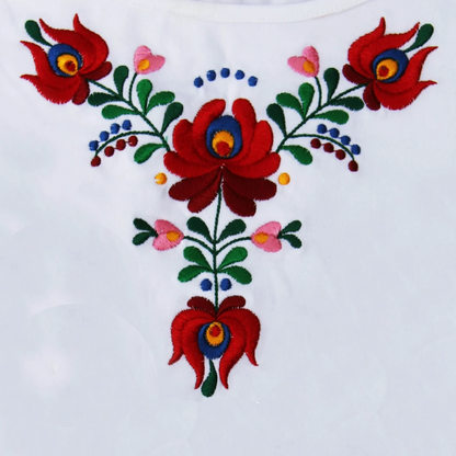 Ici la photo intégrale en plan rapproché de la broderie de ce Tshirt . Les deux nuances de rouge des fleurs agrémentées du vert des feuilles ainsi que de touches discrètes de bleu et de rose forment un ensemble harmonieux et symétrique.
