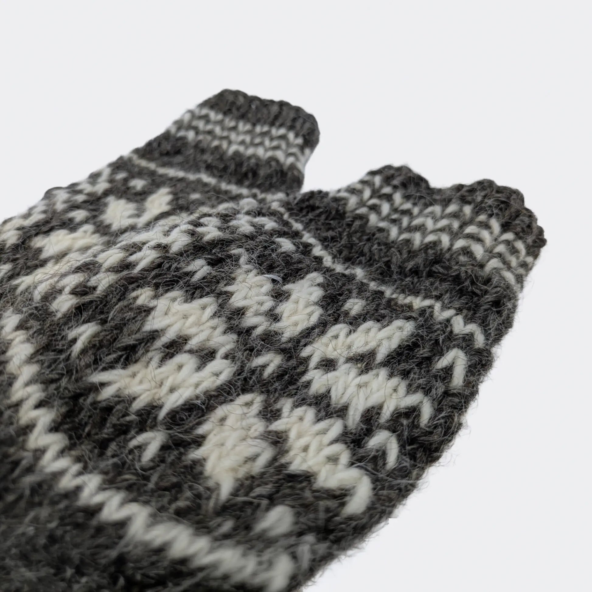 Gros plan sur la tige de chaussettes en laine grise. Les motifs écrus sont tricotés dans la maille. Chaussettes chaudes en laine à finition simple.