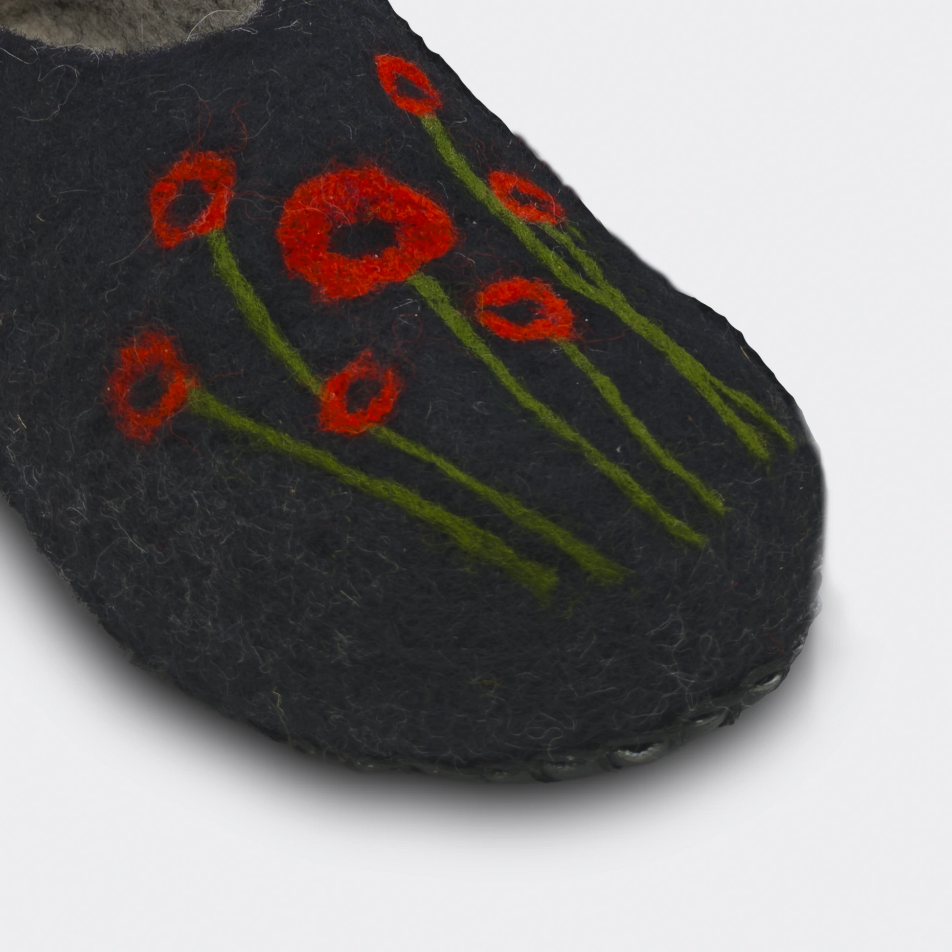 Vue en détail d'un chausson en feutre artisanal, noir avec coquelicots