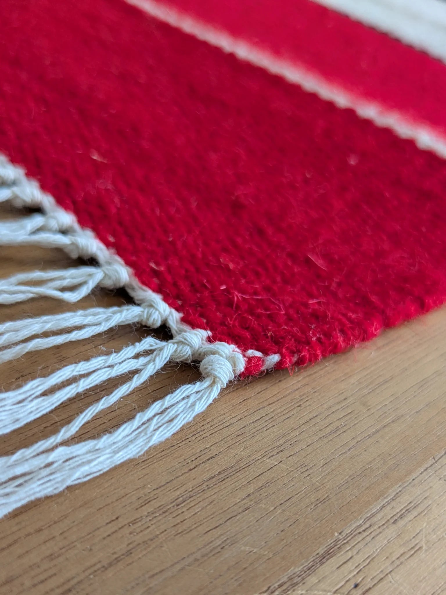 Détail des franges d’un tapis kilim rouge, tissé à plat en laine