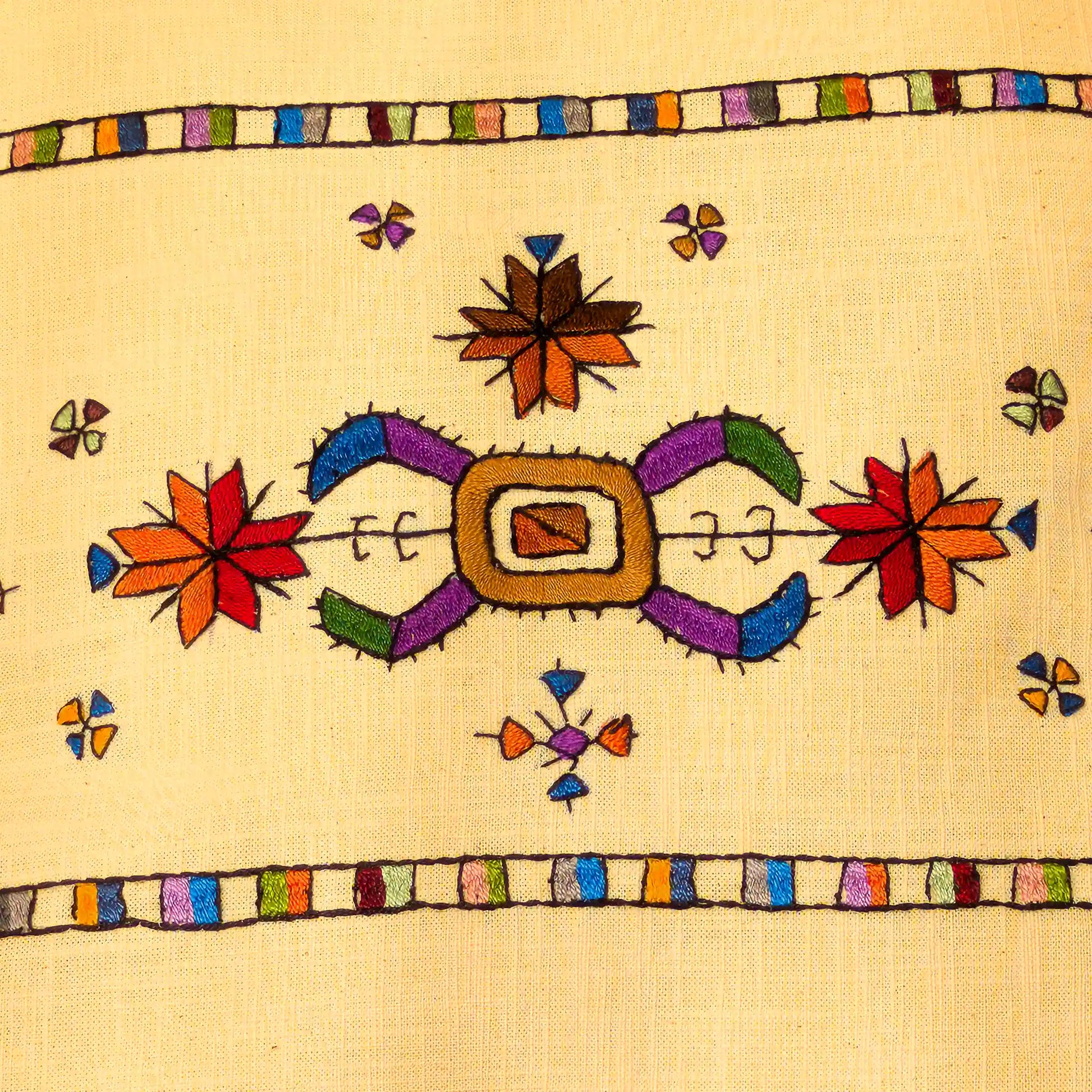 Broderie colorée du Kosovo en gros plan sur une housse de coussin en lin lavé.