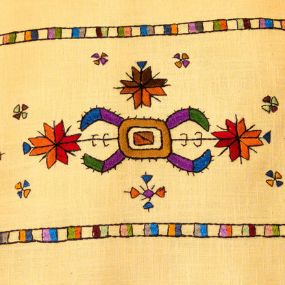 Broderie colorée du Kosovo en gros plan sur une housse de coussin en lin lavé.