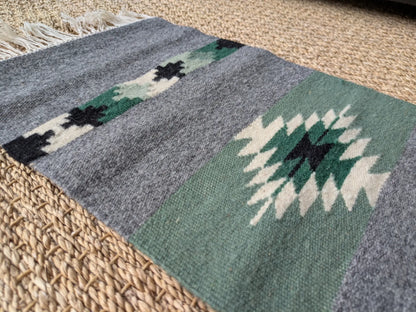 Détail du tissage laine gris vert avec un losange central. Texture dense et régulière. Motif géométrique balkanique tissé à la main.