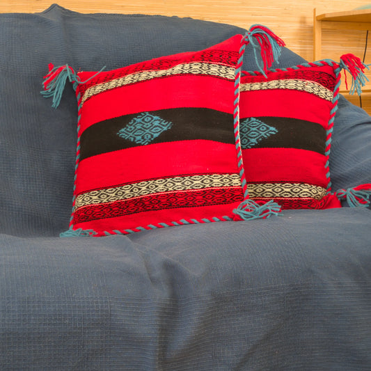 Paire de housses 45×45 en laine tissée à la main. Motifs géométriques alignés, bord tressé visible