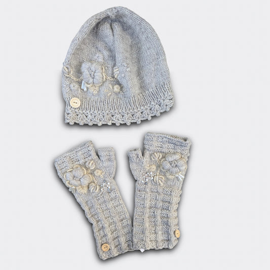 Ensemble artisanal tricoté main gris clair, bonnet et mitaines décorés de fleurs beige-écru.