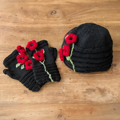 Bonnet et mitaines assortis noirs posés à plat, décorés de grands coquelicots rouges en relief.