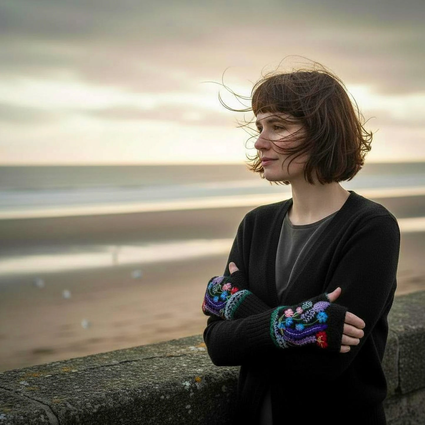 Vue de mitaines noires couvertes de fleurs multicolores et portées en extérieur.