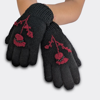 Gants noirs portés mains croisées, tricotés main avec chardon pourpre brodé et rangée de perles noires.