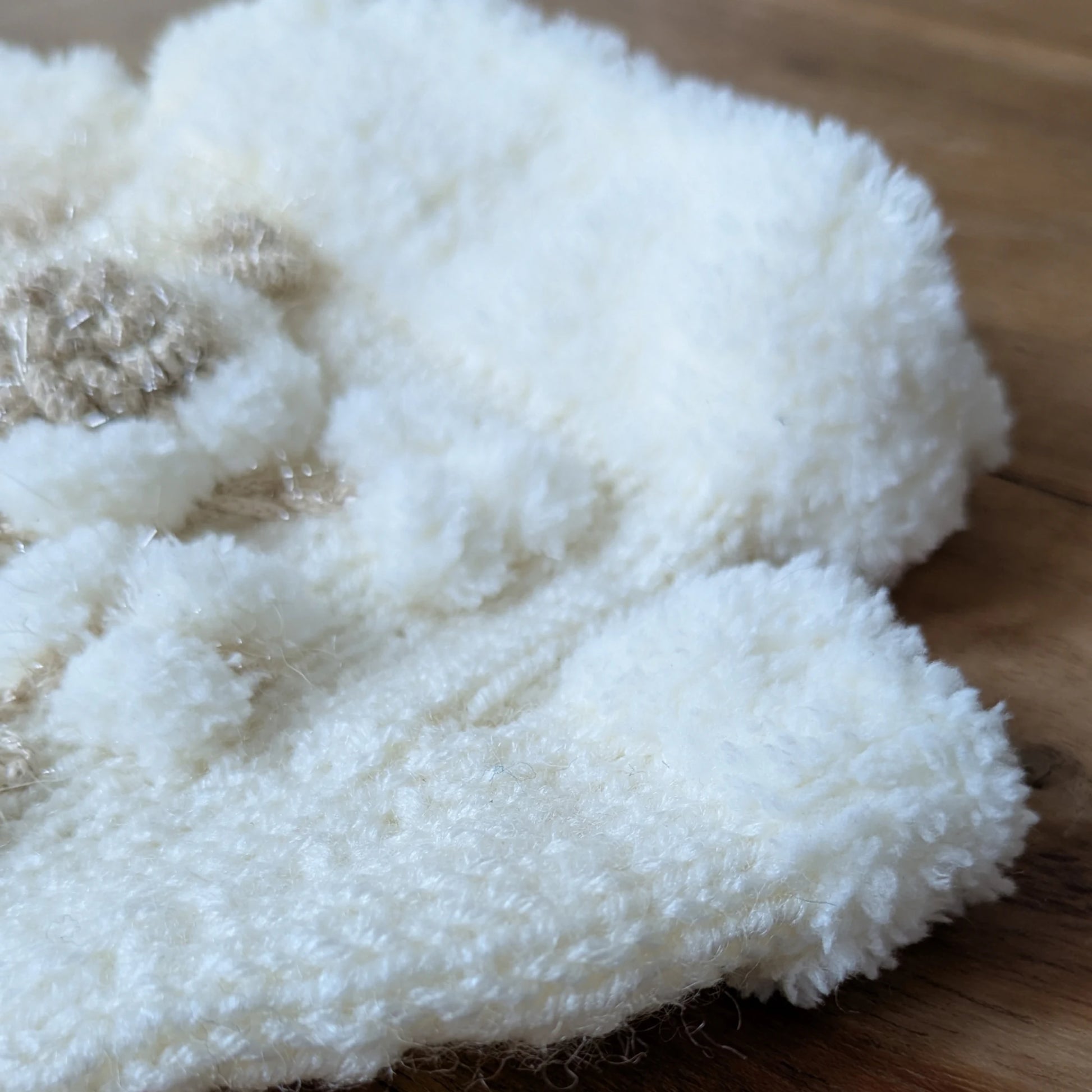 Détail de l’ourlet pelucheux blanc sur des gants sans doigts faits main.