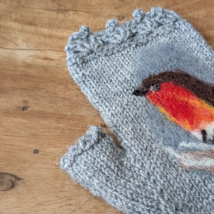 Gros plan sur le rouge-gorge en feutrage à sec et le bord festonné de ces gants sans doigts gris.