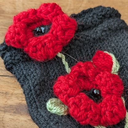 Gros plan sur les coquelicots rouges crochetés et les perles noires au centre des fleurs.