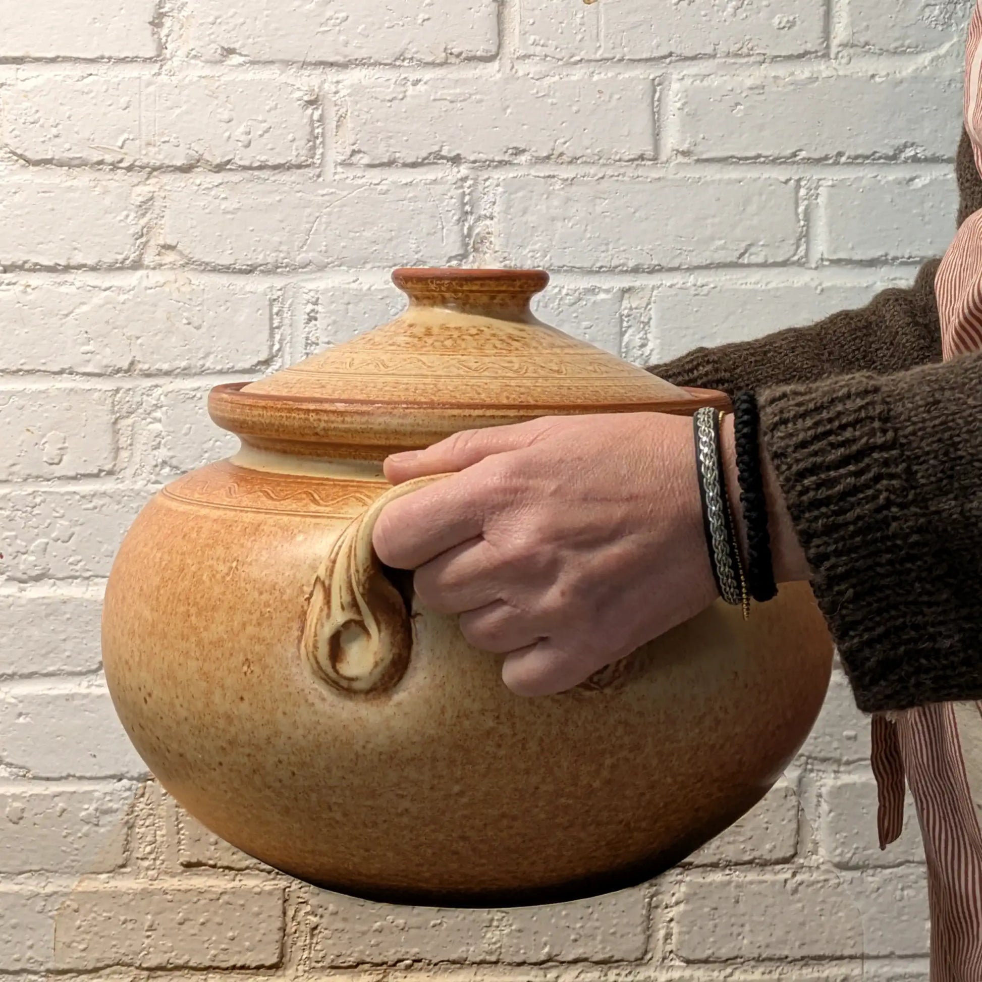 Grande cocotte en terre cuite 10 litres tenue dans les mains, poterie artisanale roumaine pour cuisine familiale.