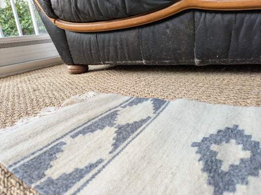 Vue rapprochée du tapis crème bleu, laine tissée main. Un motif géométrique simple. Une finition artisanale soignée.