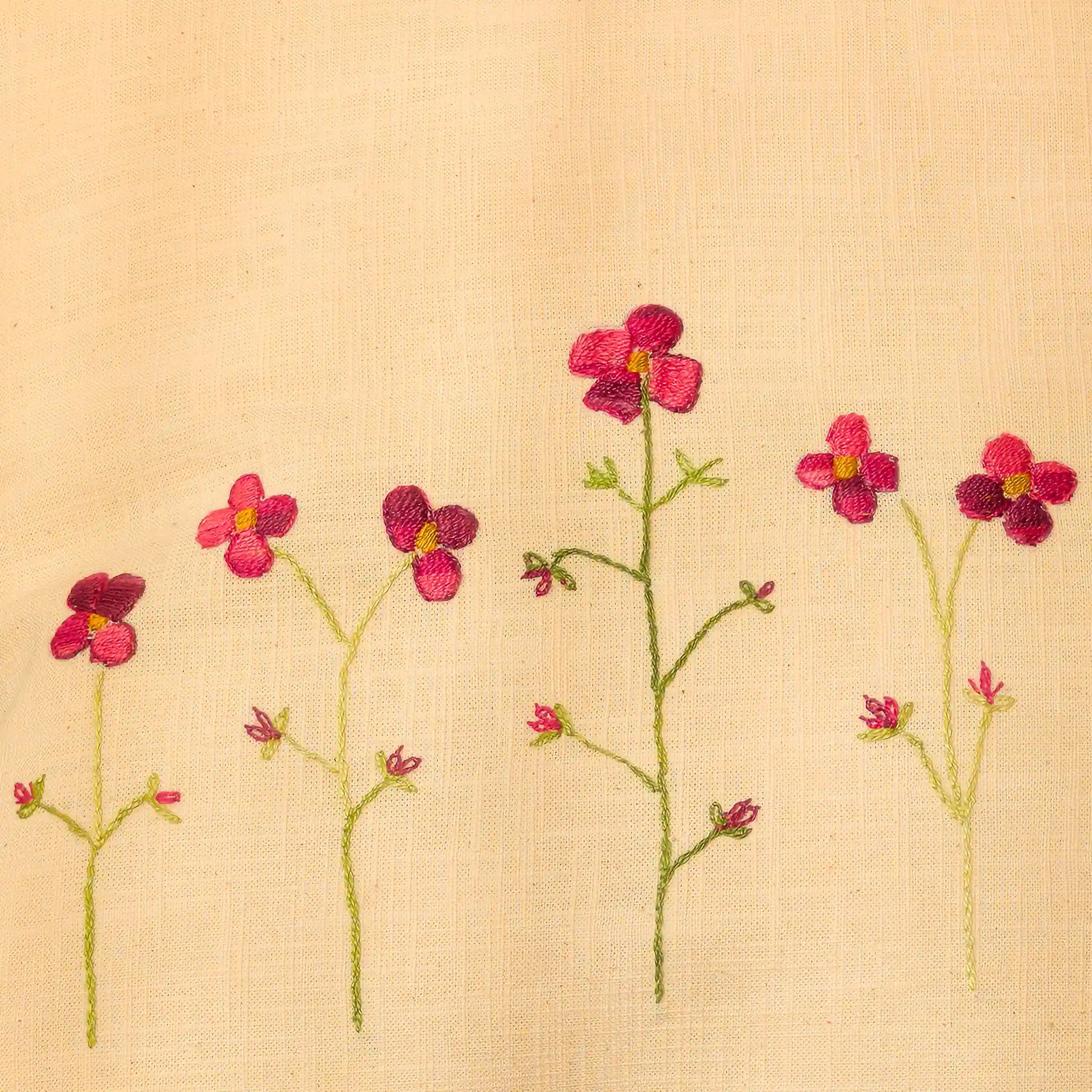 Gros plan sur une rangée de coquelicots, montée leur tige verte élancée. Un travail fin sur lin jaune pastel.