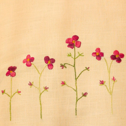 Gros plan sur une rangée de coquelicots, montée leur tige verte élancée. Un travail fin sur lin jaune pastel.