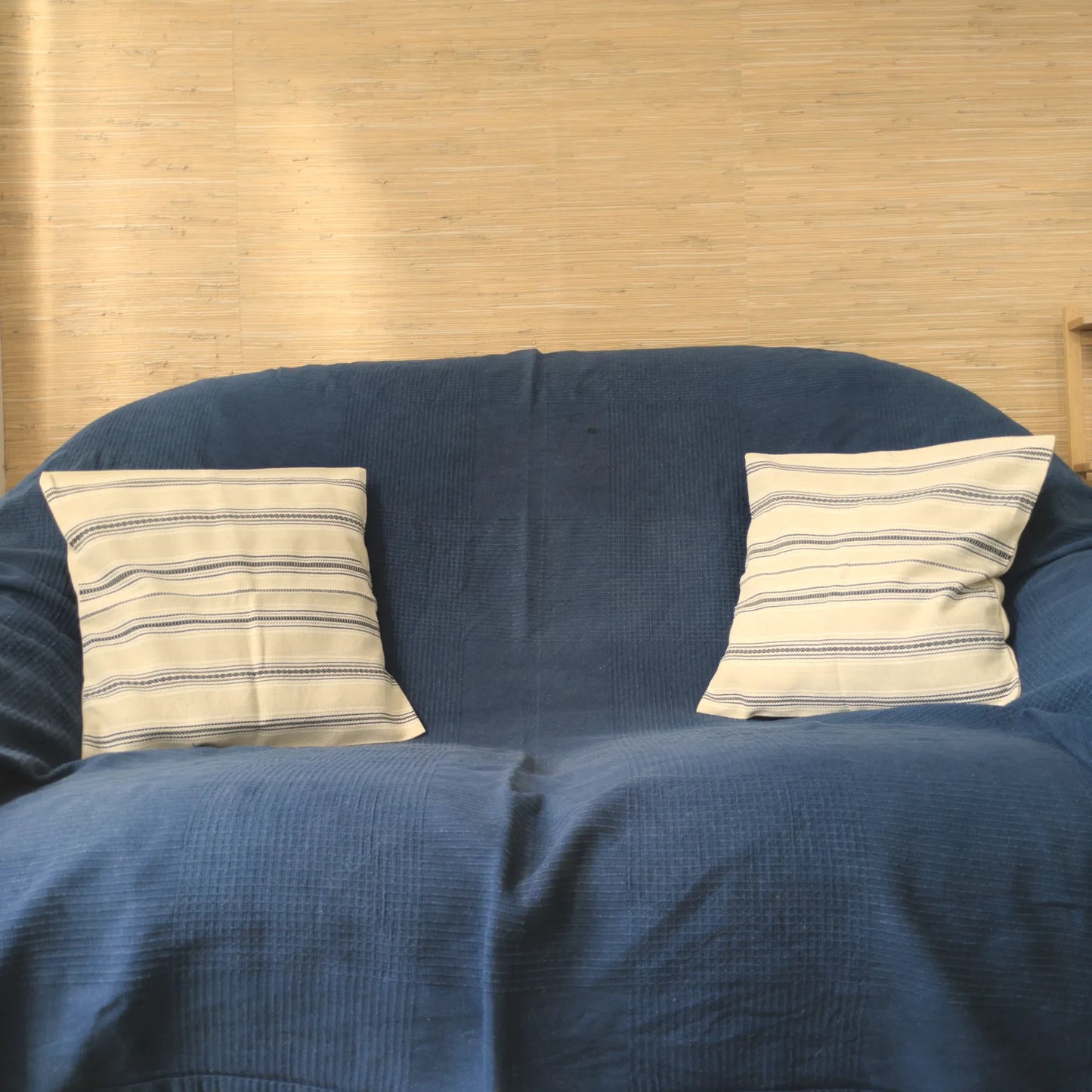 Deux coussins avec une housse tissée à la main par un artisan, 40x40cm en coton. Coloris noir et crème. Vue sur canapé.