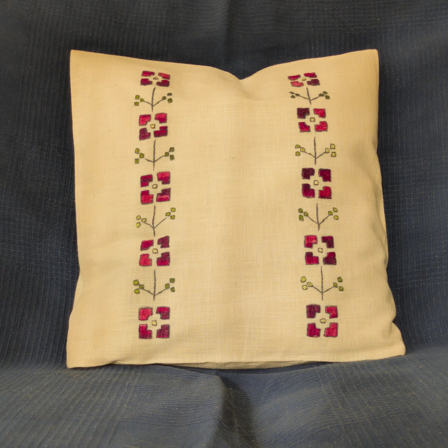 Housse en lin naturel brodée main avec des fleurs stylisées rouges. Les pétales sont séparés en quatre blocs. Un motif inspiré de l’Est.