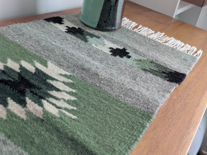 Kilim vert olive et gris tissé à plat en laine, vu en angle avec motifs traditionnels des Balkans