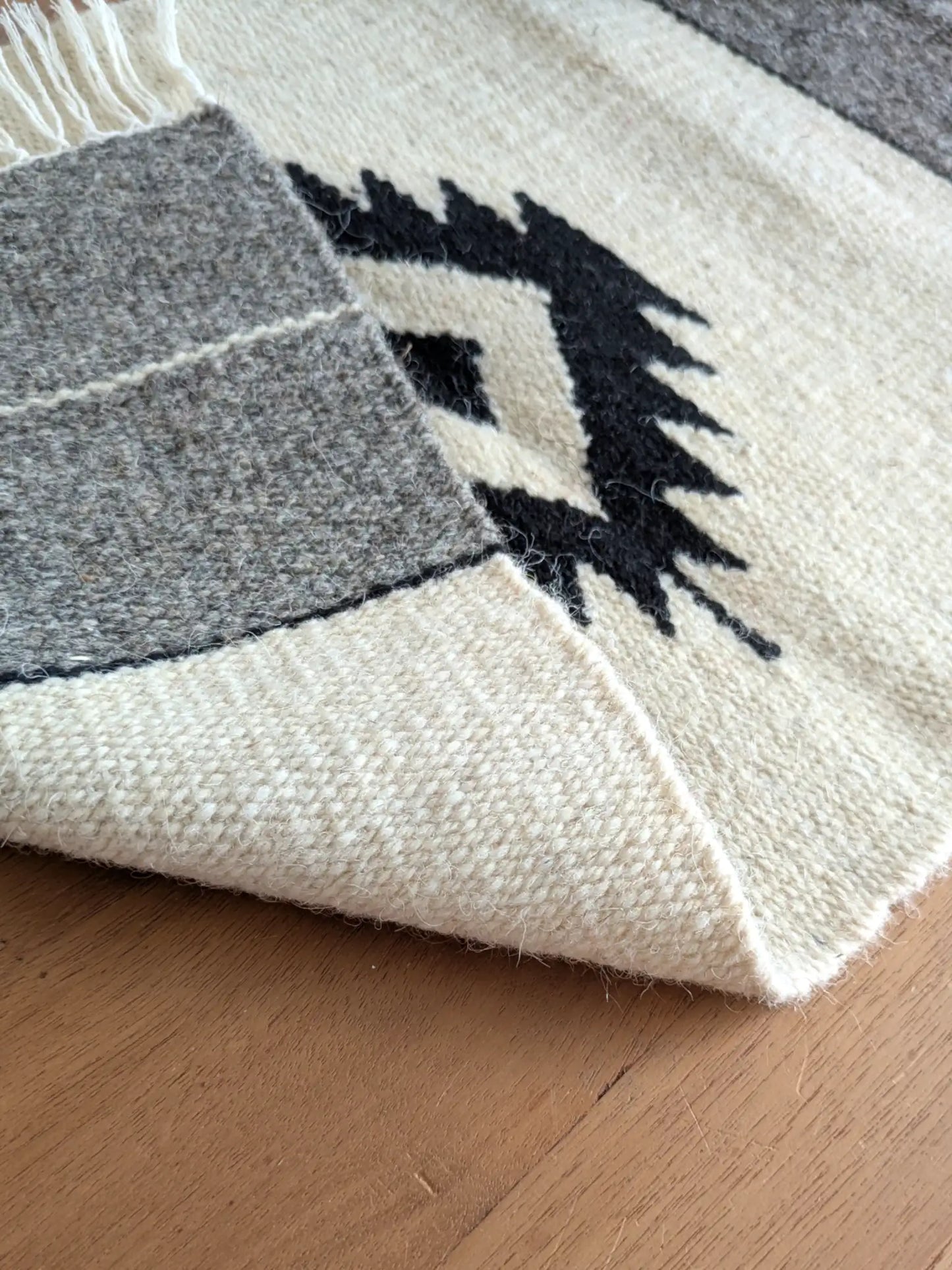 Kilim réversible crème et gris, replié pour montrer un tissage identique à l’endroit et à l’envers
