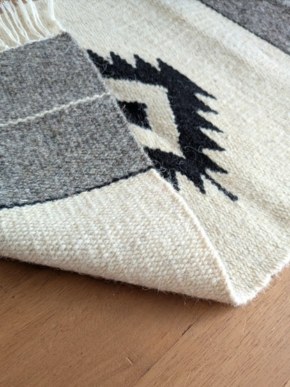 Kilim réversible crème et gris, replié pour montrer un tissage identique à l’endroit et à l’envers