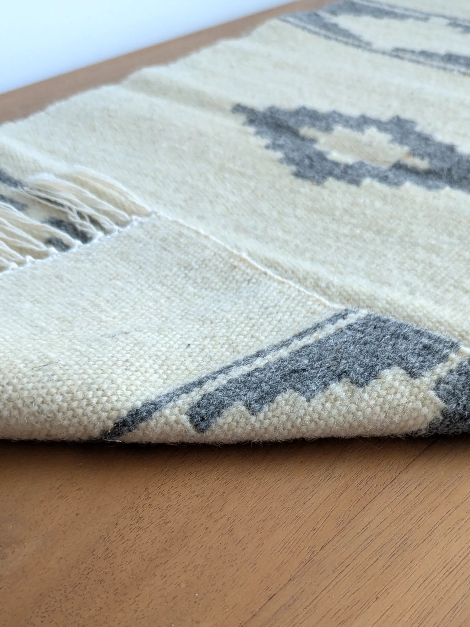 Kilim réversible gris et crème, replié pour montrer l’endroit et l’envers du tissage