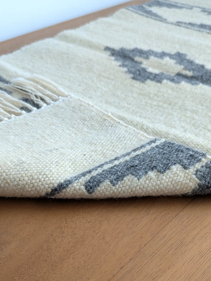 Kilim réversible gris et crème, replié pour montrer l’endroit et l’envers du tissage